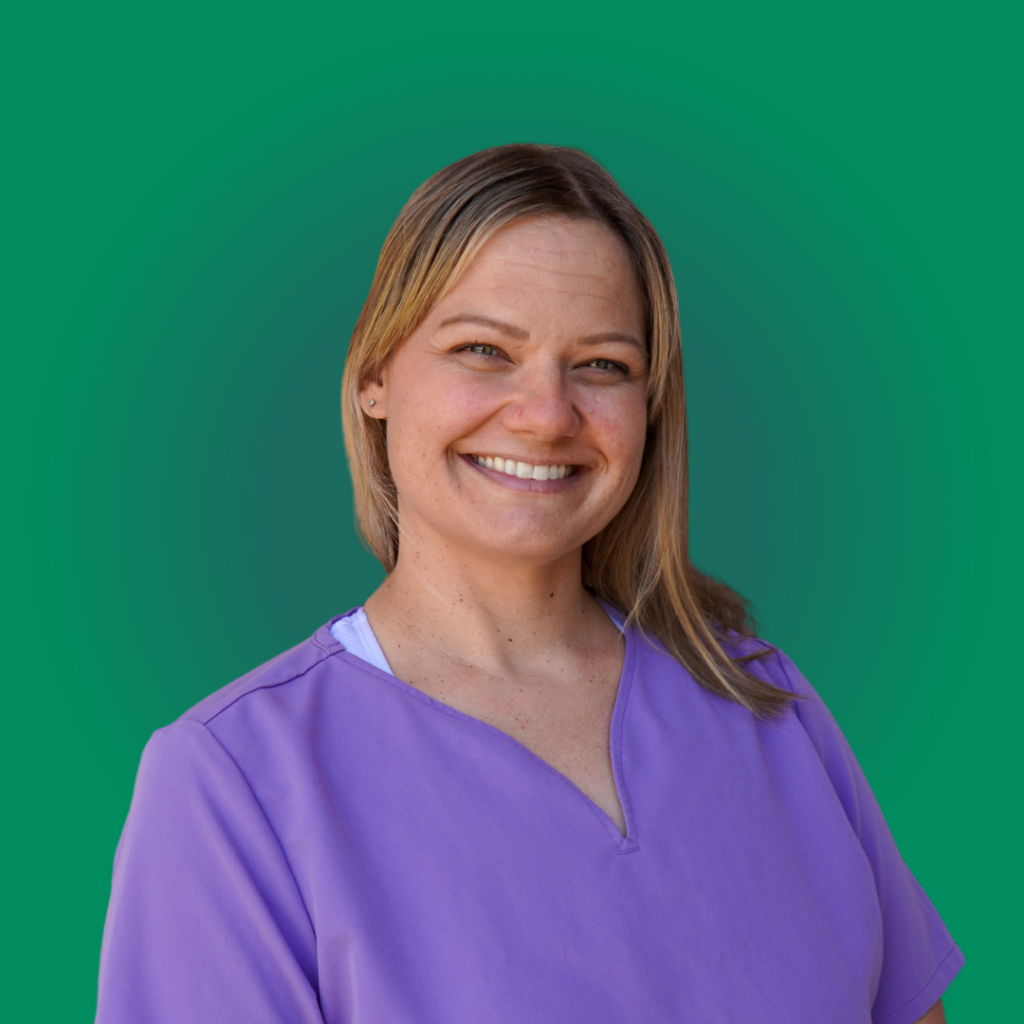 Portrait of a smiling dental team member with blonde hair wearing purple scrubs against a solid green background at Dr. Shirley Zhao's Pleasanton office.