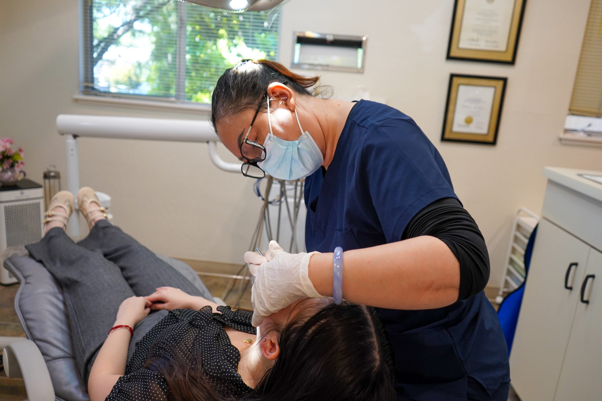 Dentist using advanced instruments to carefully examine a patient lying in a modern treatment chair.