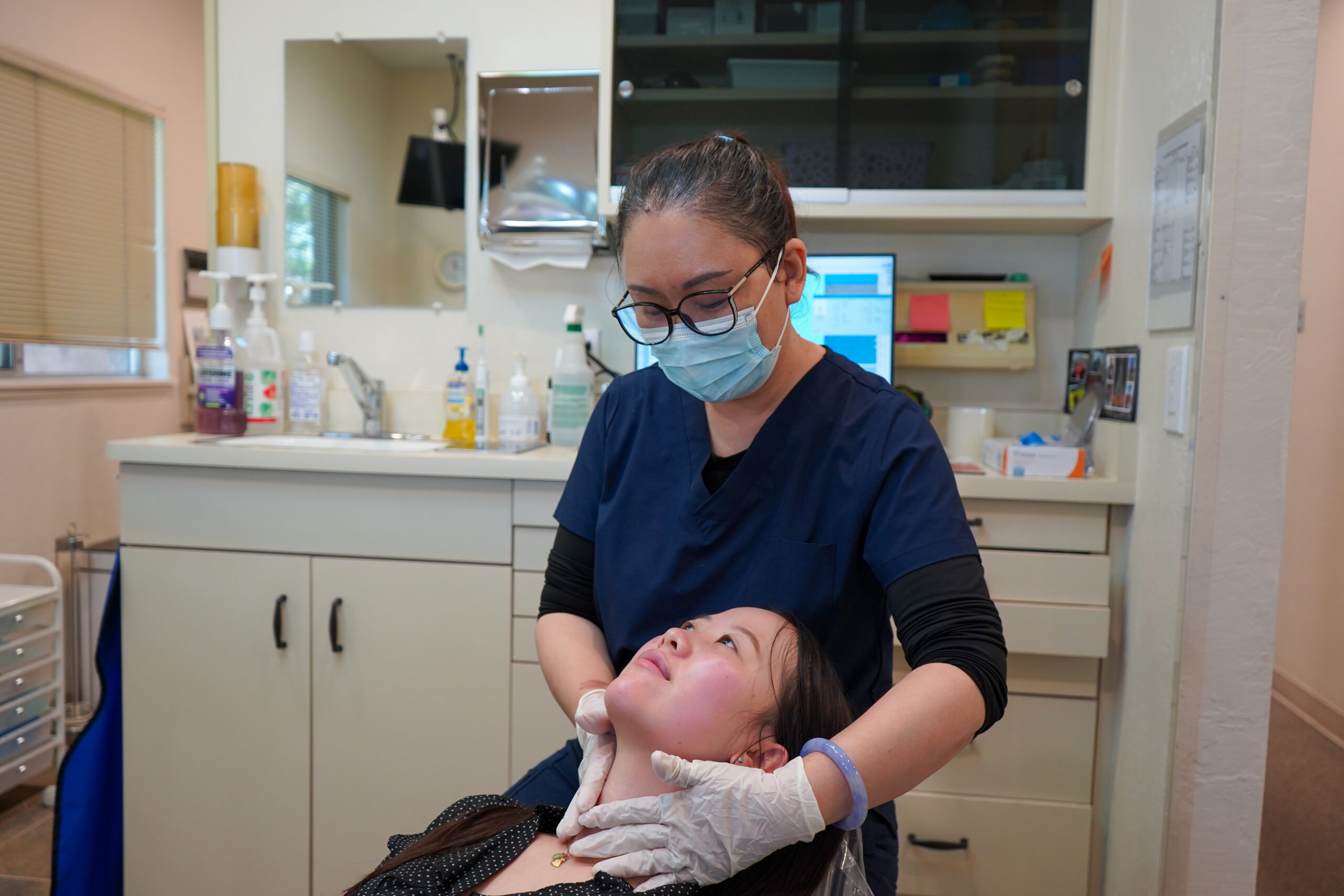 Dr. Shirley Zhao performing a gentle neck and jaw examination on a patient during a routine dental checkup.